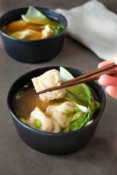 chicken Wonton was picked in the chopsticks and soup is in the bowl