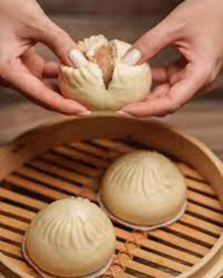 a chef is tearing the dumpling bun revealing the inside filling of Pork