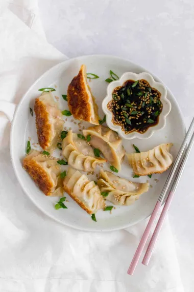 top view of Kimchi Pork Dumplings with the sauce garnished