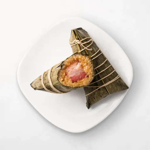 A top view of Kurobuta Pork Sticky Rice Wrap placed in a plate in two slice