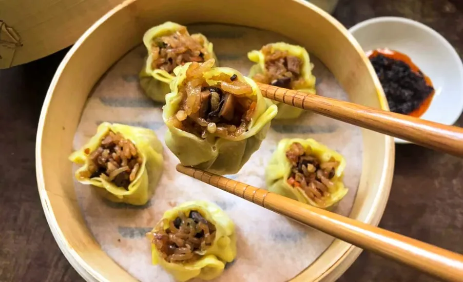Shao Mai dumpling picked witht he choopstick filled with rice and Kurobuta pork