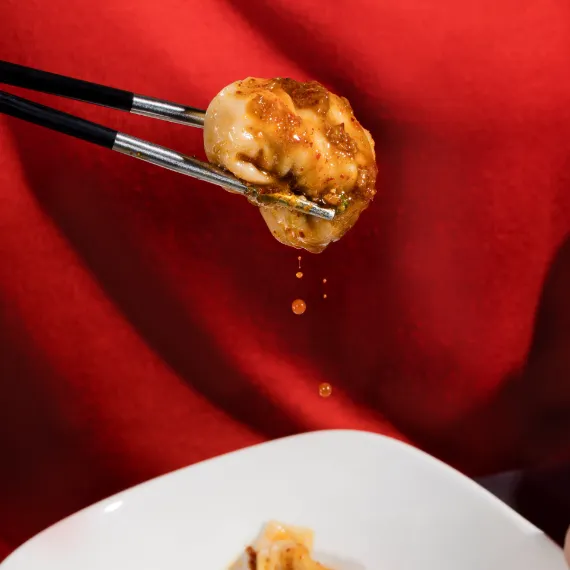 a dumpling dippend in the Wonton Soup is picked wit the chopsticks