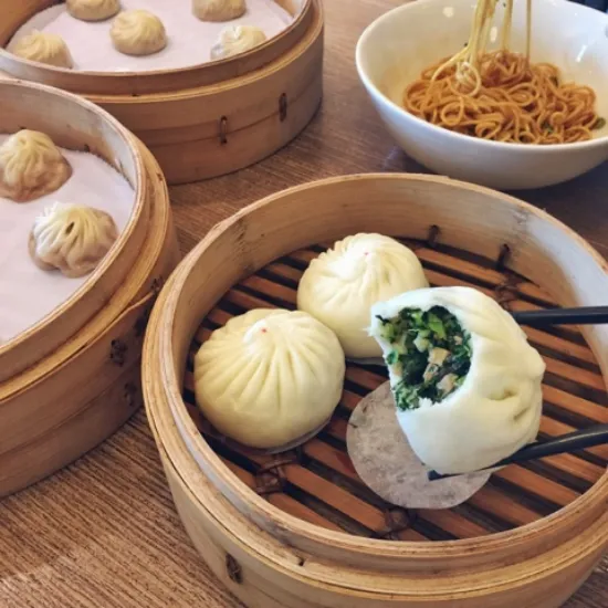 Vegan Buns picked in chopstick and veggies are visible through the opening