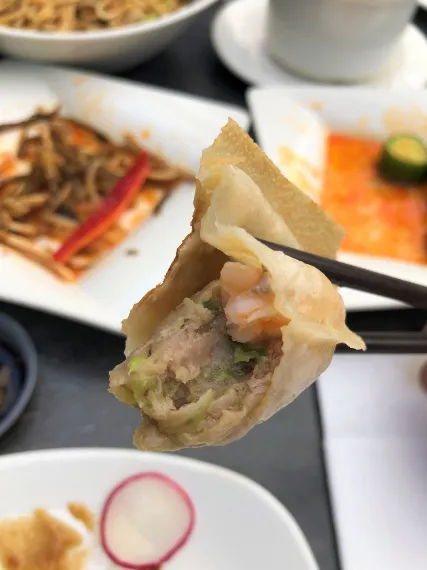 chicken is peeking from the dumpling held in chopstick