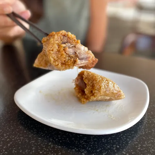a Kurobuta Pork Sticky Rice Wrap is picked in a chopstick ready to eat