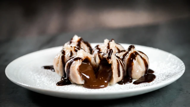 Mochi and chocolate-filled xiao long bao served on a plate with rich melted chocolate oozing from the center.